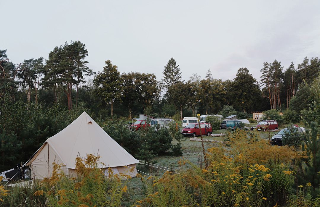 Campingplatz mit Zelt und Wohnwagen in der Abendstimmung.